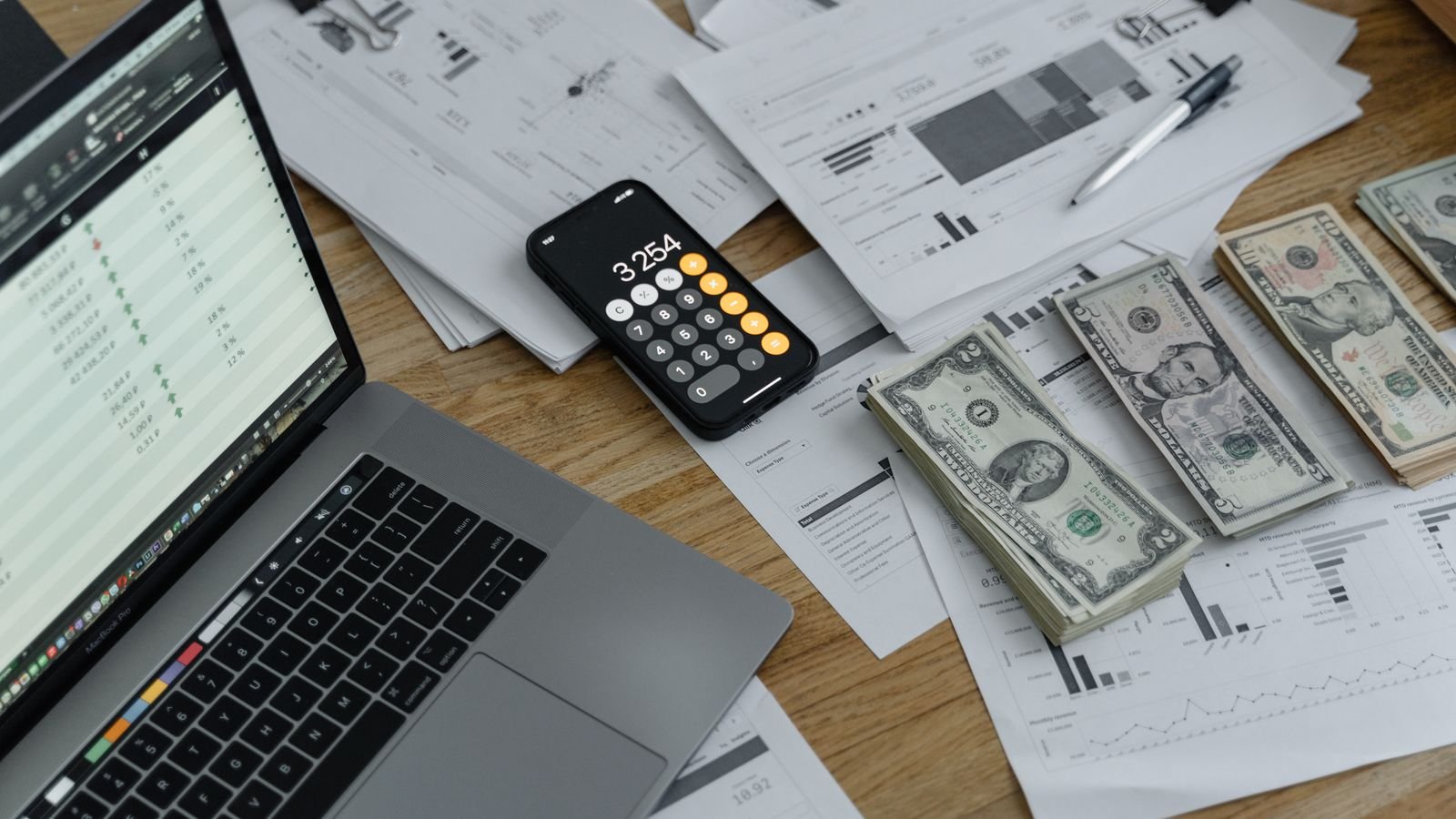 Close-up of hands counting dollar bills over documents with a calculator, representing student loan repayment budgeting