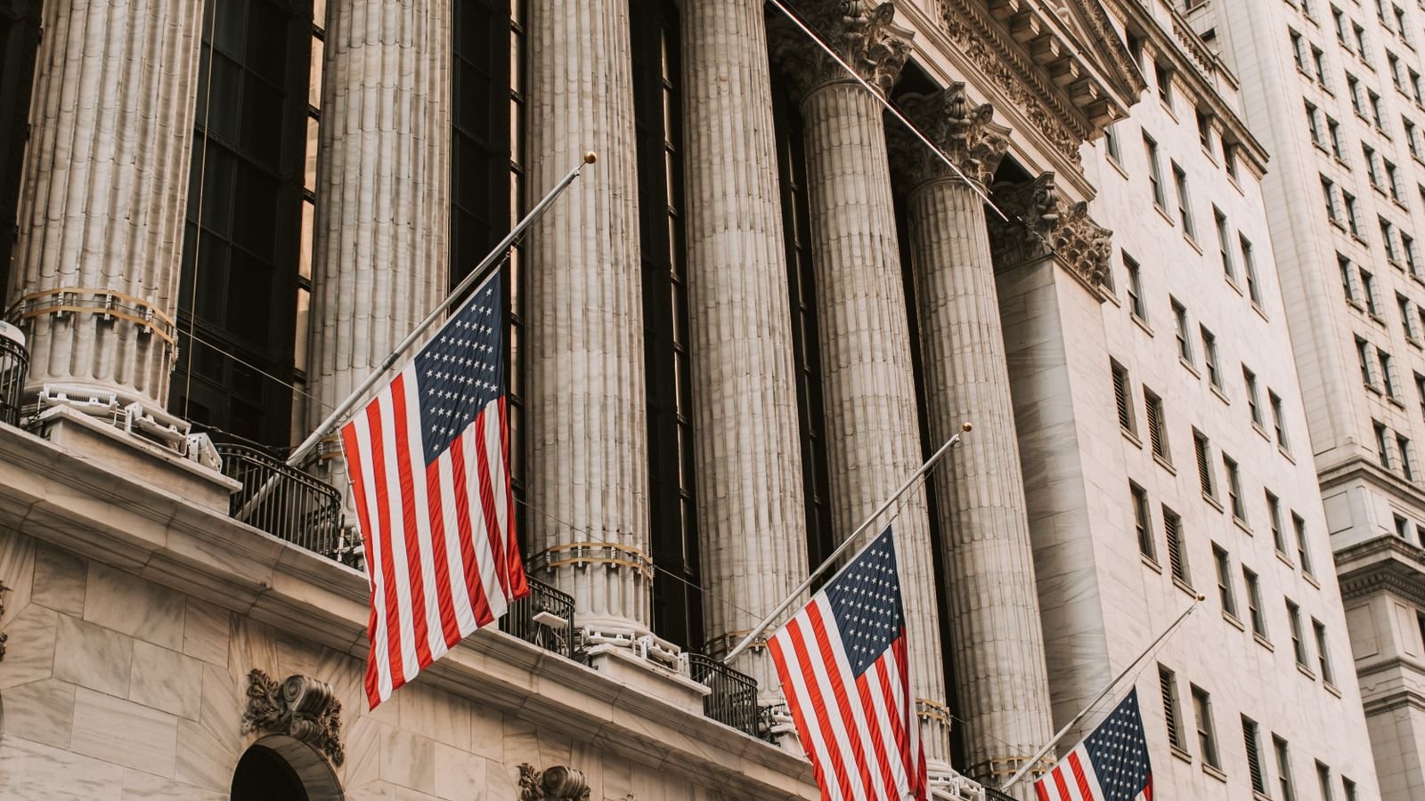 Iconic New York Stock Exchange with American flags on Wall Street, representing stocks near record highs amid banking sector news