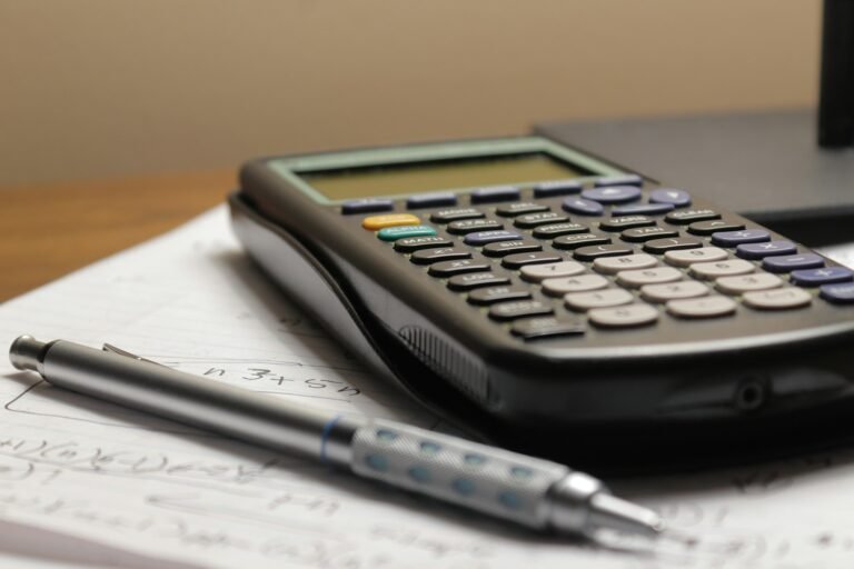 Calculator and pen resting on a sheet of paper, representing comparing loan costs