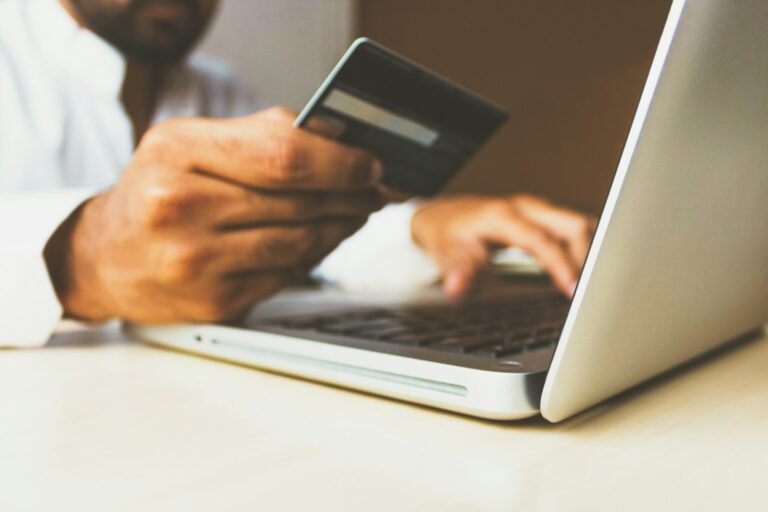 Person using a laptop while holding a credit card to manage card debt