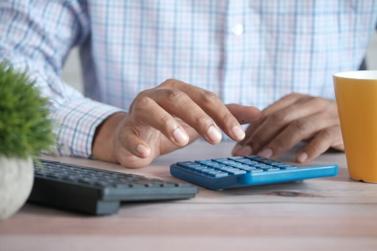 Person using a calculator at a desk to work out loan affordability