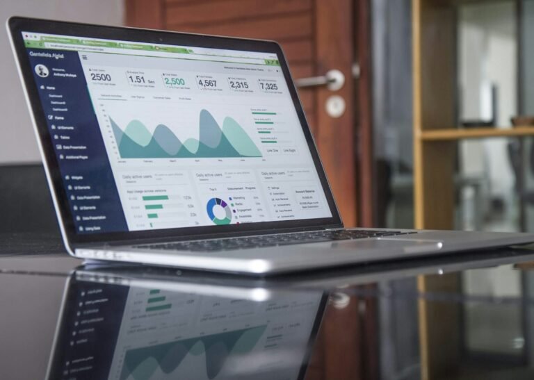 Laptop displaying financial statistics on a glass-top table